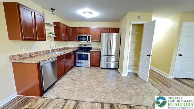 a large kitchen with stainless steel appliances granite countertop a refrigerator a stove top oven a sink and dishwasher