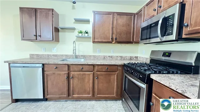 a kitchen with stainless steel appliances granite countertop a stove a sink and a microwave
