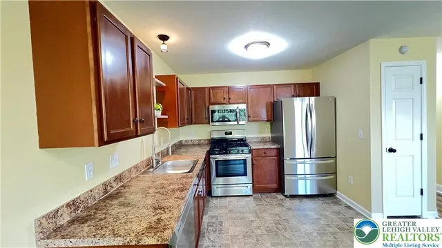a kitchen with stainless steel appliances granite countertop a refrigerator a stove and a sink with wooden floor