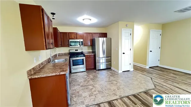 a kitchen with stainless steel appliances granite countertop a refrigerator a stove and a sink