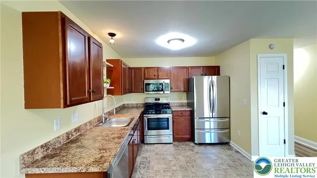 a kitchen with stainless steel appliances granite countertop a refrigerator and a stove top oven