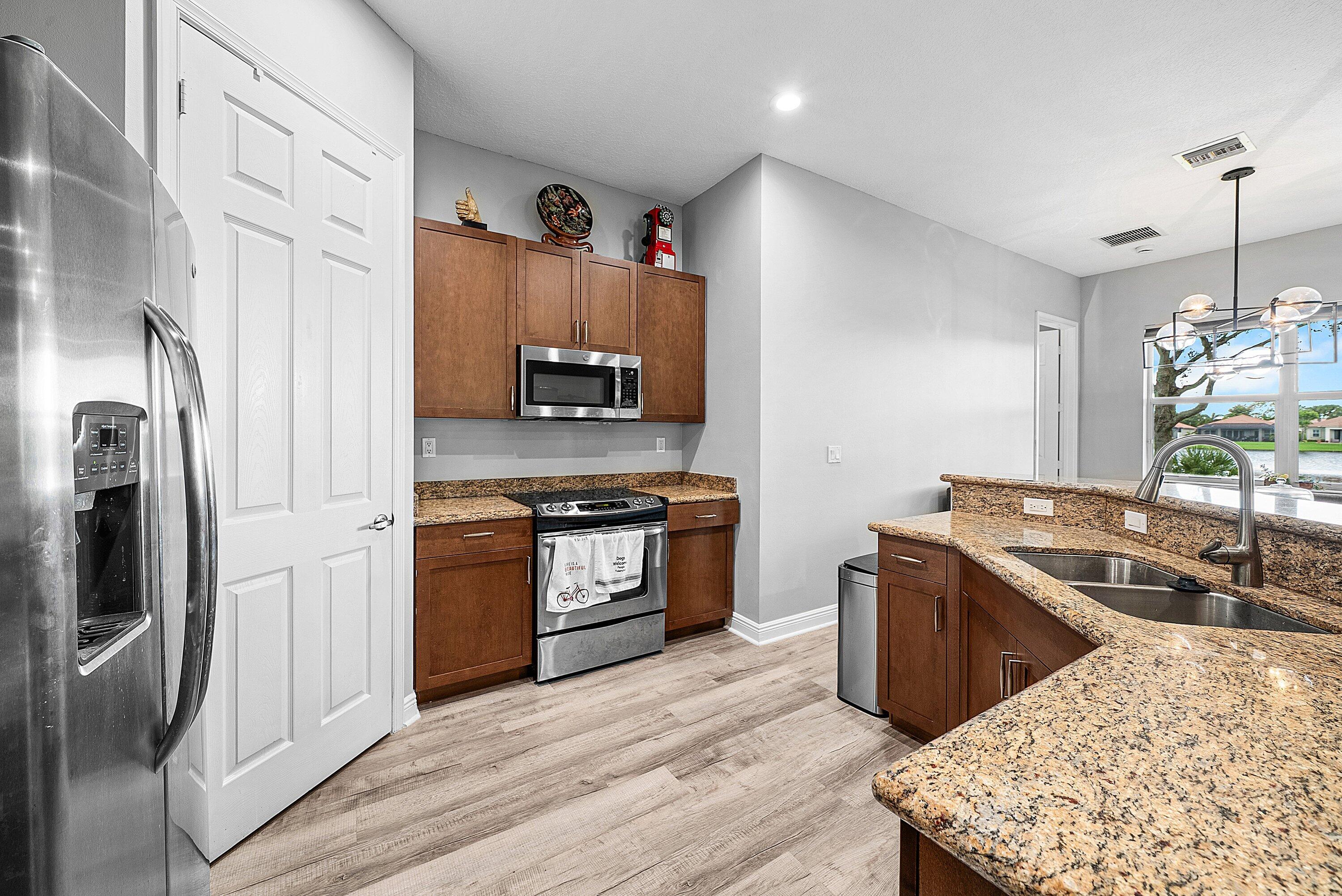 14841 Strand Lane, Unit 14841 Delray Beach, FL 33446 - Photo 12 of 43 a kitchen with stainless steel appliances granite countertop a sink stove and refrigerator