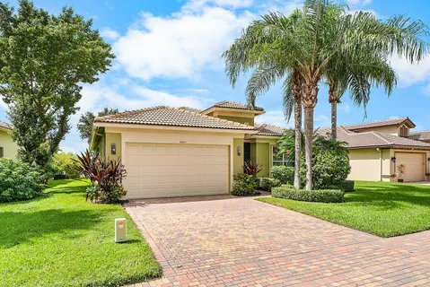 a front view of a house with a garden and palm trees