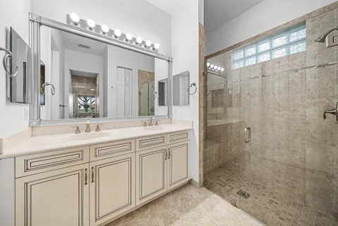 a bathroom with a double vanity sink mirror and shower