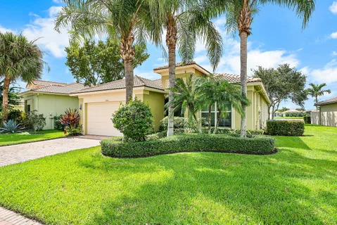 a view of a house with a yard and palm trees