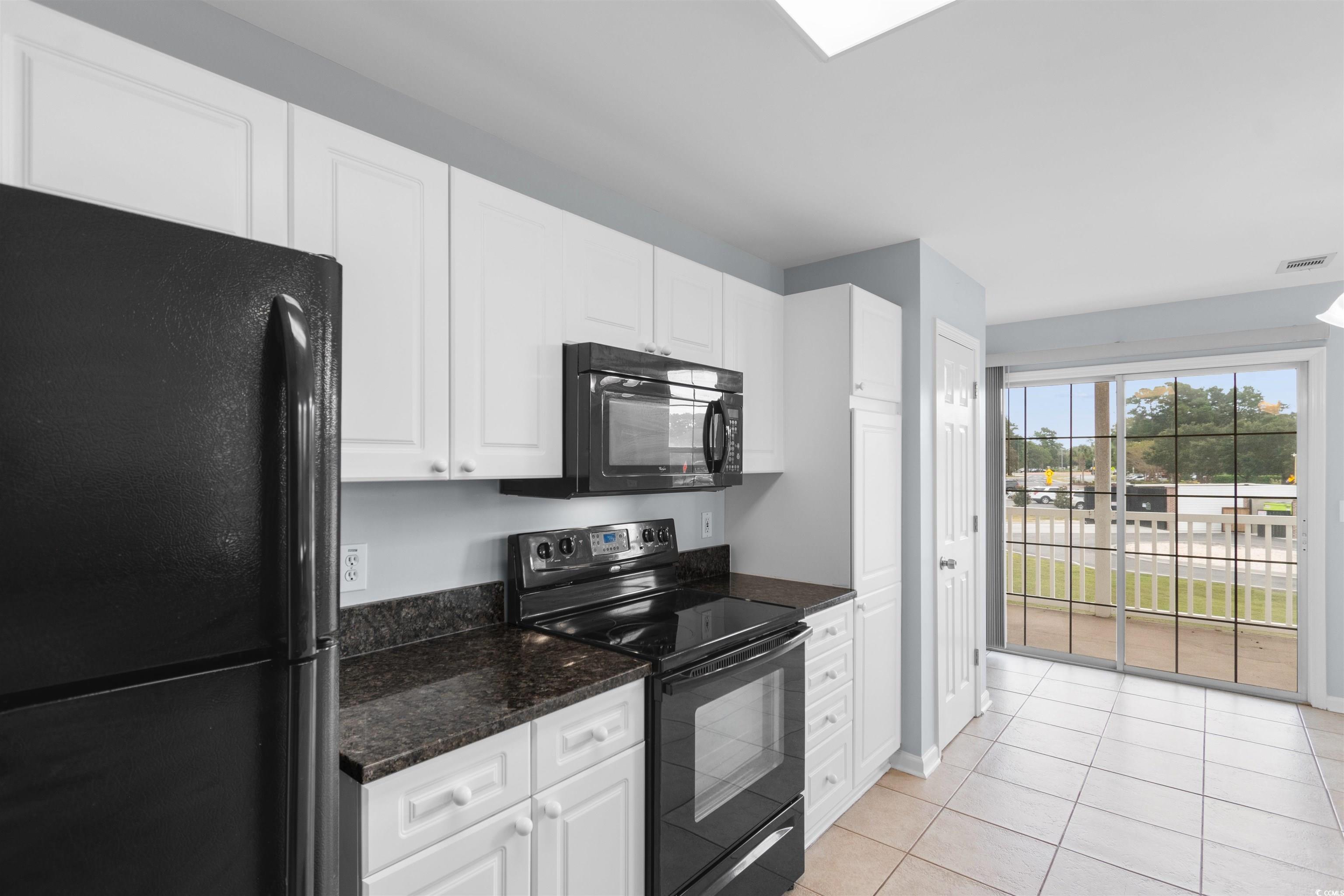 4430 Lady Banks Lane, Unit A2 Murrells Inlet, SC 29576 - Photo 10 of 31 Kitchen featuring black appliances, white cabinets, light tile patterned floors, and dark stone counters