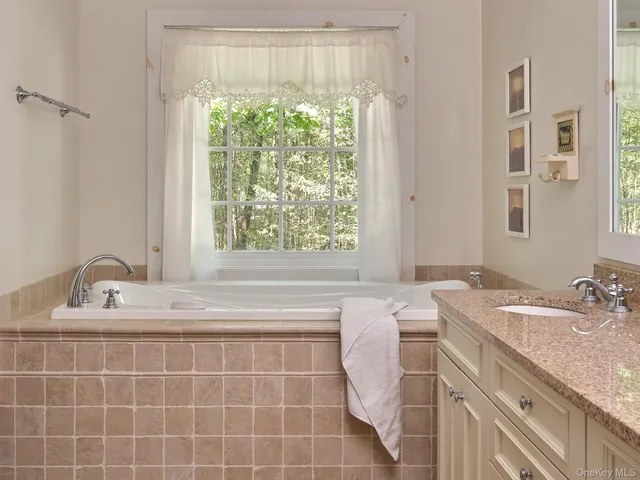 a bathroom with a granite countertop sink and a window