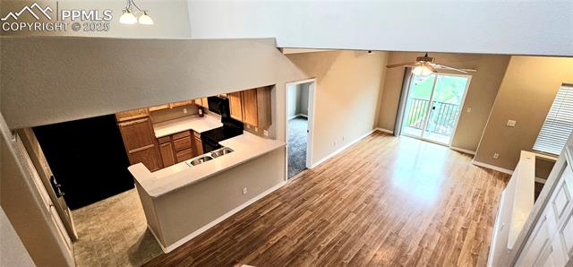 6967 Stetson Ranch Point, Unit 204 Colorado Springs, CO 80922 - Photo 2 of 13 Unfurnished living room with light wood-type flooring, a ceiling fan, baseboards, and a sink