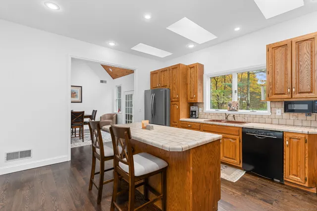 a open kitchen with granite countertop a dining table chairs and a refrigerator