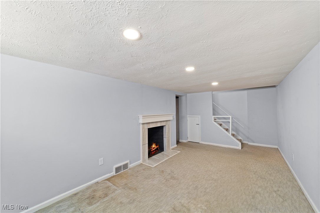 4249 Stonehaven Road Cleveland, OH 44121 - Photo 30 of 33 Basement featuring a textured ceiling, a tile fireplace, and carpet flooring