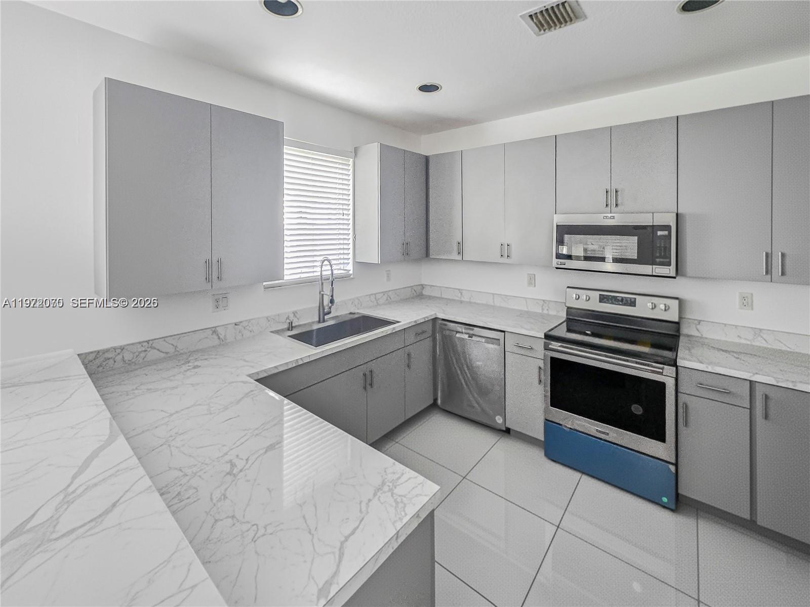 15843 Southwest 139th Street Miami, FL 33196 - Photo 12 of 39 a kitchen with a sink stove and cabinets