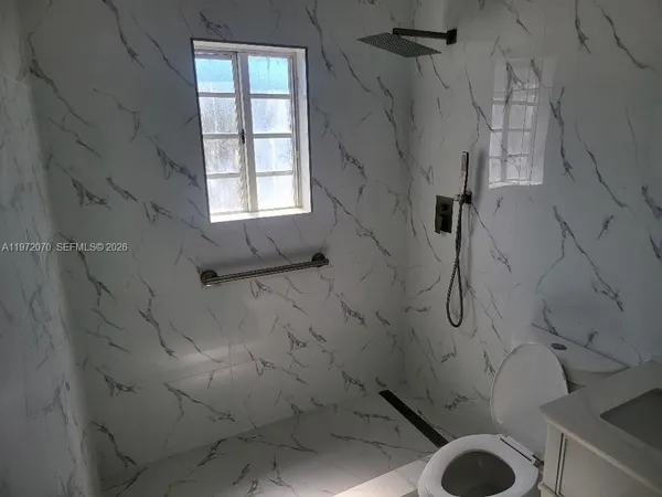 a bathroom with a granite countertop sink toilet and shower