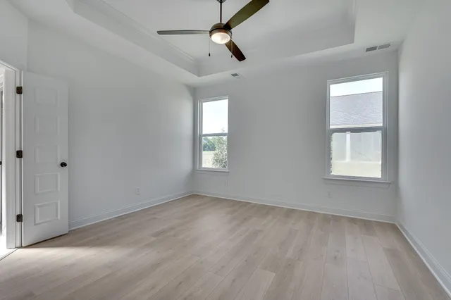 an empty room with windows and fan