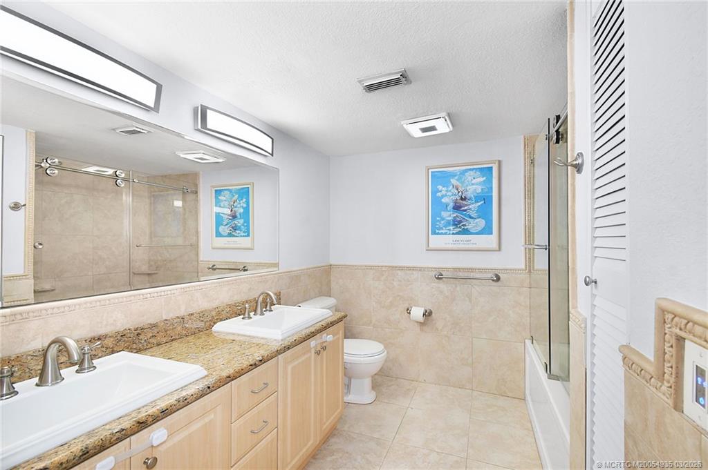 3129 Southeast Indian Street, Unit 3 Stuart, FL 34997 - Photo 19 of 28 a bathroom with a granite countertop sink a toilet a mirror and shower
