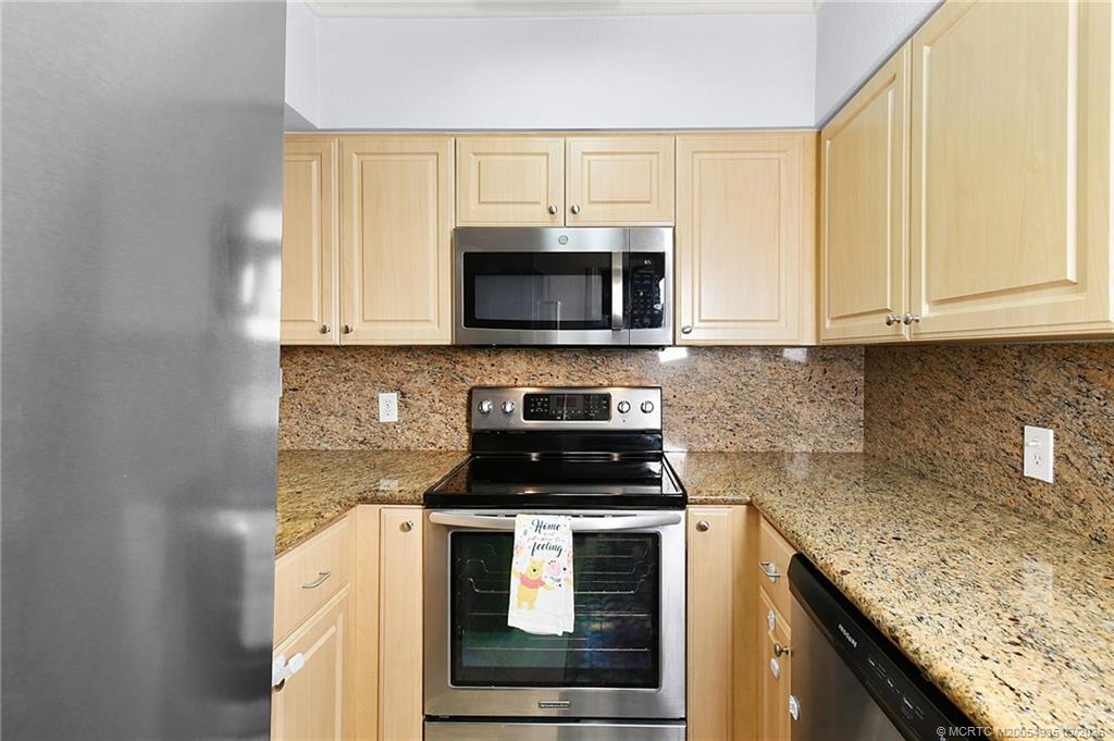 3129 Southeast Indian Street, Unit 3 Stuart, FL 34997 - Photo 9 of 28 a kitchen with granite countertop white cabinets and black appliances
