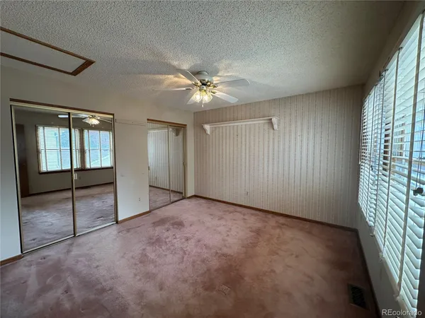 an empty room with windows and fan