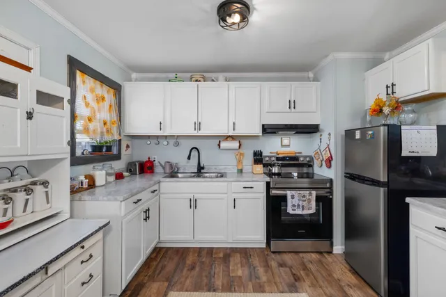 a kitchen with stainless steel appliances granite countertop a refrigerator a sink dishwasher a stove top oven a refrigerator and cabinets with wooden floor