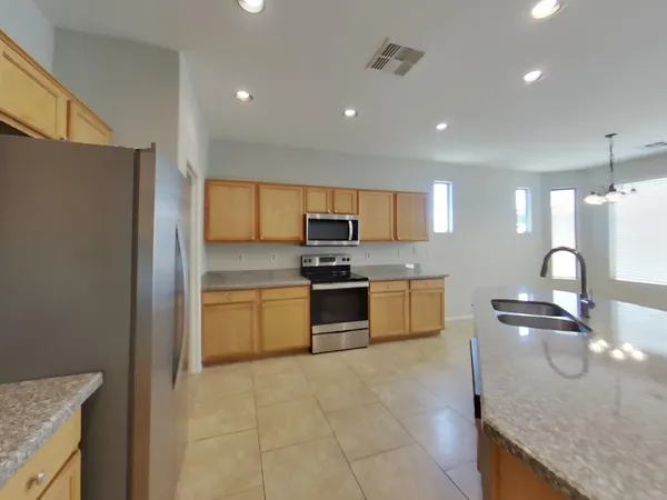 a large kitchen with granite countertop a stove top oven a sink a counter space and cabinets