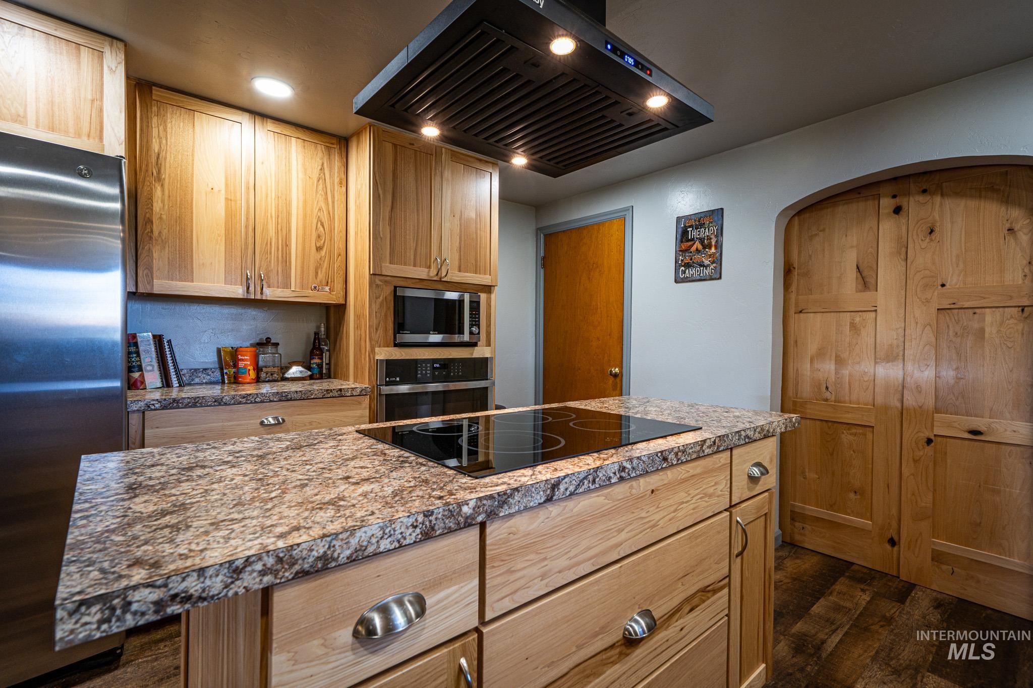 67 Jessup Road Grangeville, ID 83530 - Photo 6 of 49 Kitchen featuring wood cabinetry, stainless steel refrigerator, built-in microwave, integrated cooktop, and stone-finish countertops