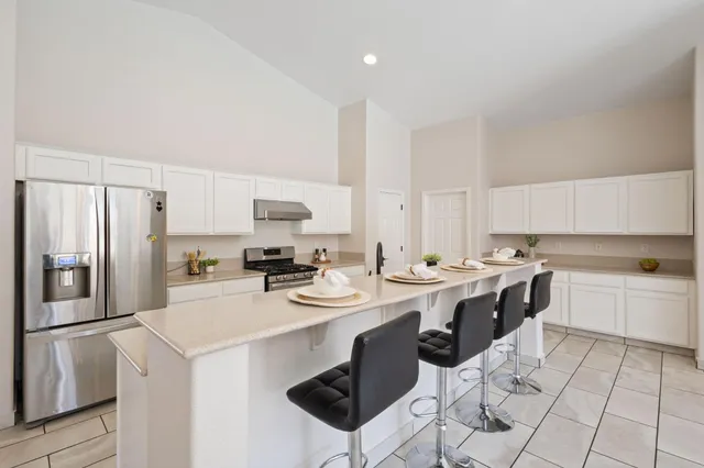 a kitchen with a sink a stove a refrigerator and white cabinets