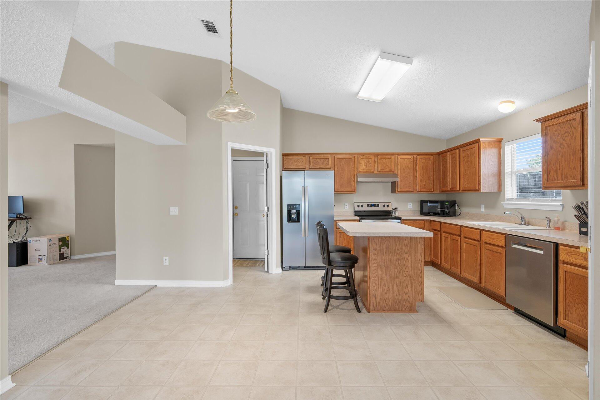 118 Sandstone Trail Crestview, FL 32539 - Photo 15 of 33 a kitchen with stainless steel appliances kitchen island granite countertop a refrigerator a sink a stove and white cabinets