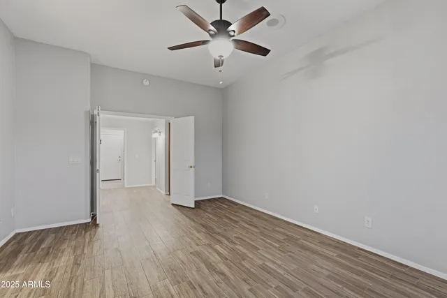 an empty room with wooden floor fan and windows
