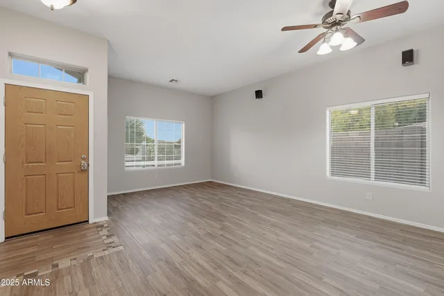 a view of an empty room with wooden floor and a window