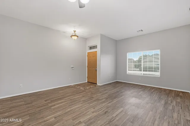 a view of an empty room with wooden floor and a window