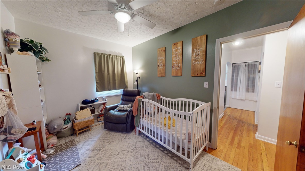 343 Canton Road Akron, OH 44312 - Photo 19 of 37 Bedroom with hardwood / wood-style floors, a crib, ceiling fan, and a textured ceiling
