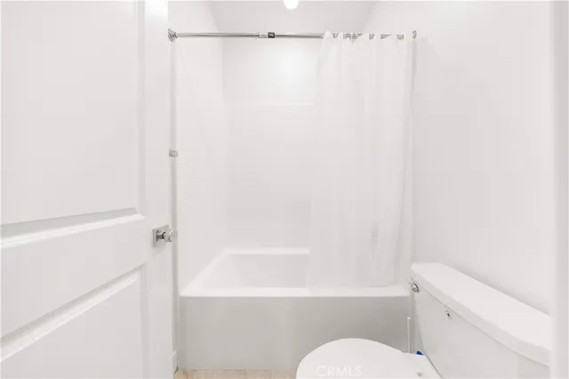 a white toilet sitting next to a white wall
