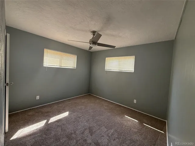 an empty room with windows and ceiling fan