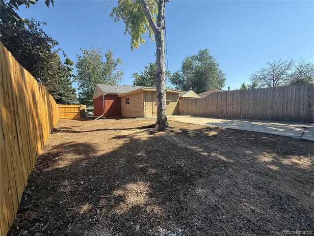 a view of backyard with wooden fence and trees