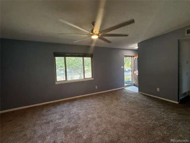 an empty room with windows and fan