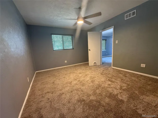 an empty room with a ceiling fan and a window