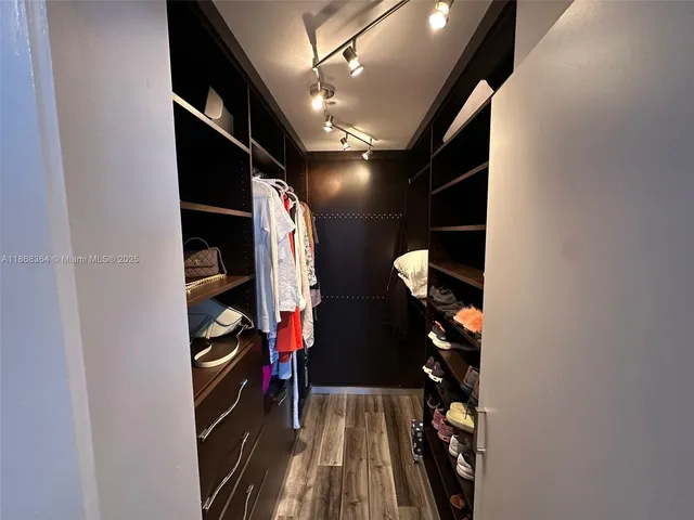 a view of walk in closet with clothes and shoes
