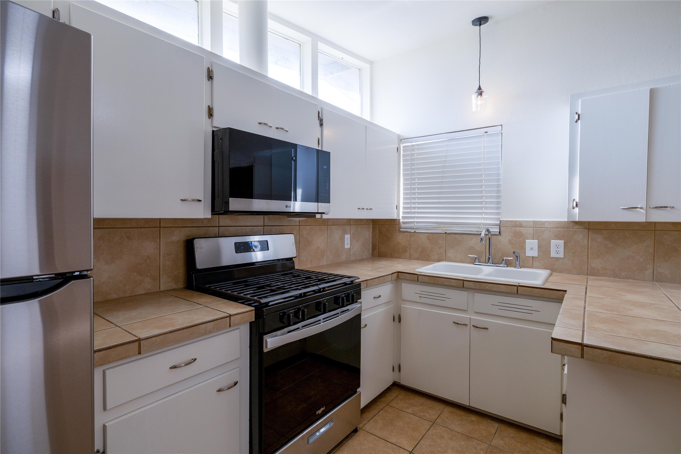 4304 Scottsdale Road Austin, TX 78721 - Photo 6 of 21 Kitchen featuring white cabinetry, tile countertops, tile backsplash, stainless steel appliances, and an undermount sink