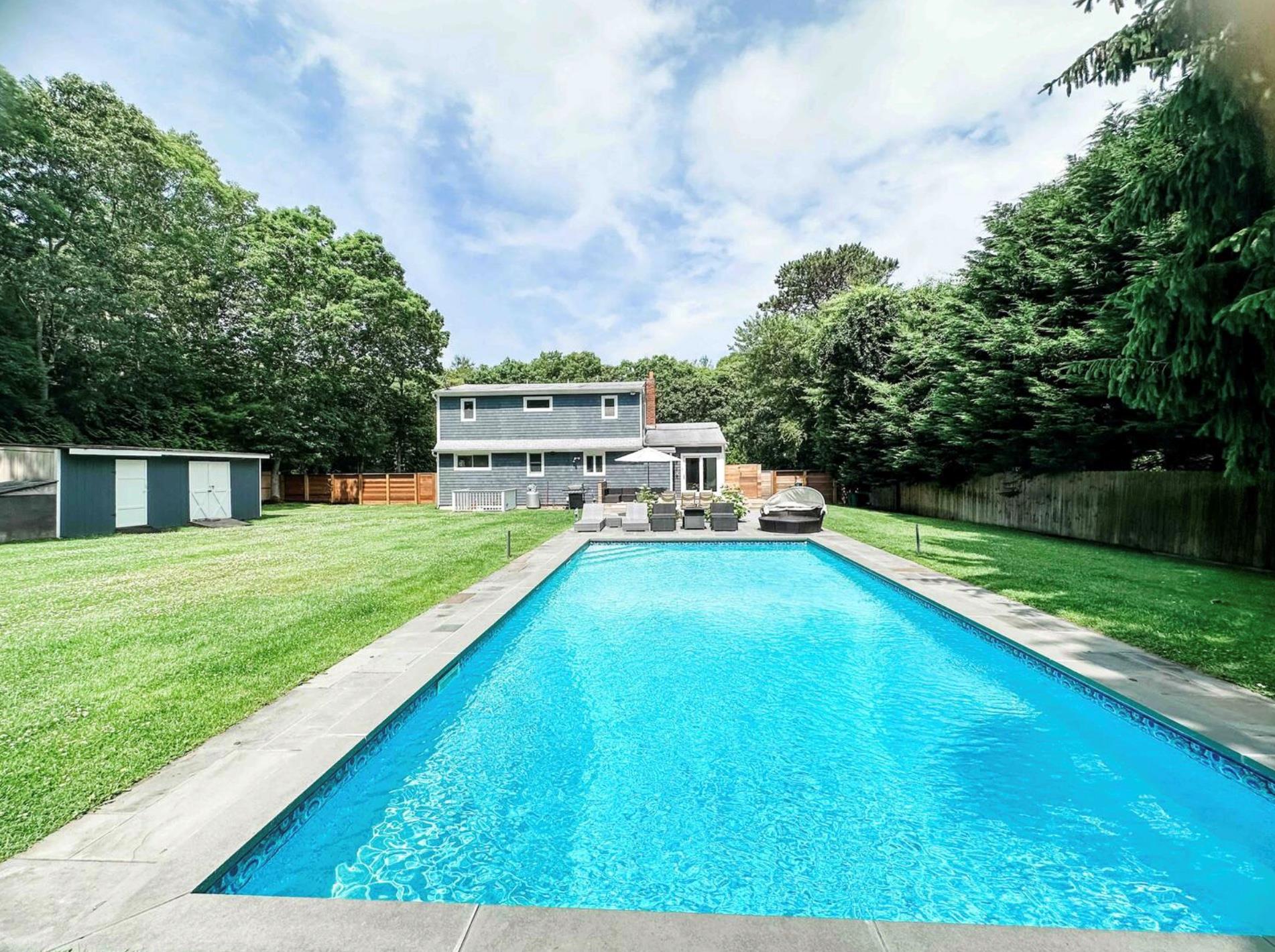 View of swimming pool featuring a lawn, a fenced backyard, an outdoor hangout area, an outbuilding, and a storage unit