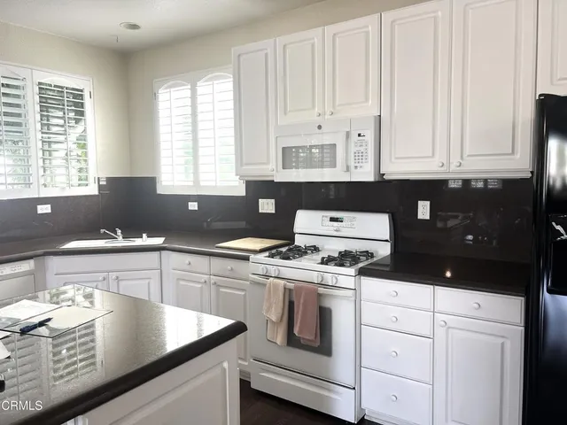 a kitchen with granite countertop white cabinets and a stove