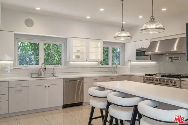 a kitchen with stainless steel appliances granite countertop a sink a stove a dining table and chairs