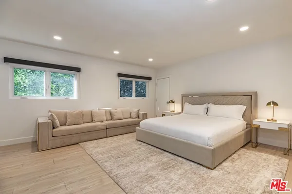 a bedroom with a large bed couch and windows