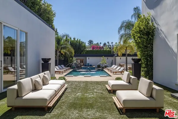a view of a patio with couches table and chairs with potted plants and big yard