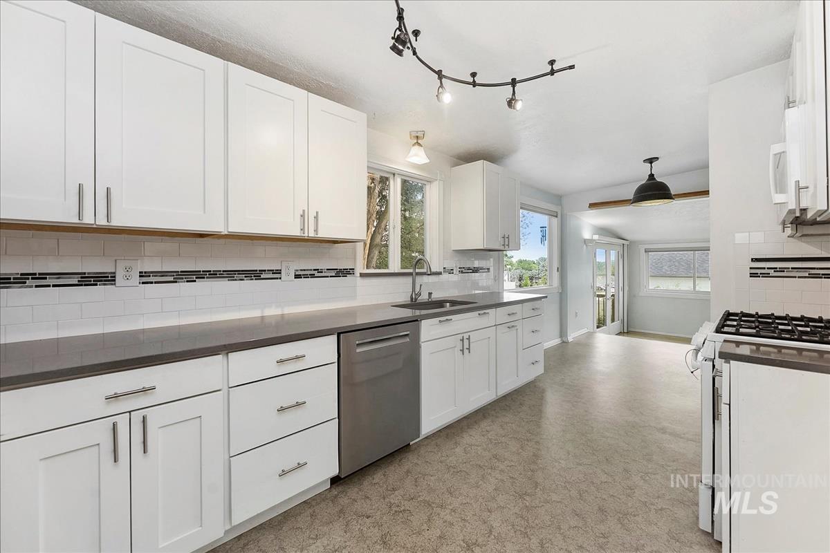 7141 West Hill Road Boise, ID 83714 - Photo 7 of 28 Multi-level interior featuring hardwood flooring, a built-in wood display shelf with interior windows, a kitchen with white cabinetry, stainless steel appliances, and a pendant light fixture