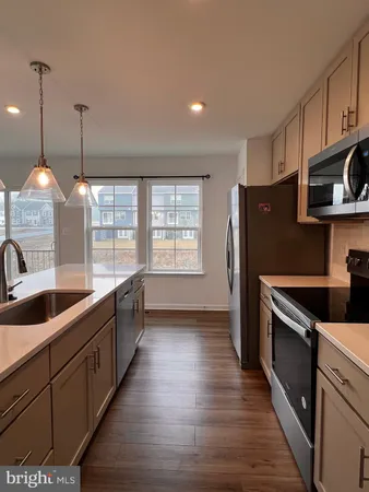 a kitchen with granite countertop a stove a sink a refrigerator and wooden cabinets