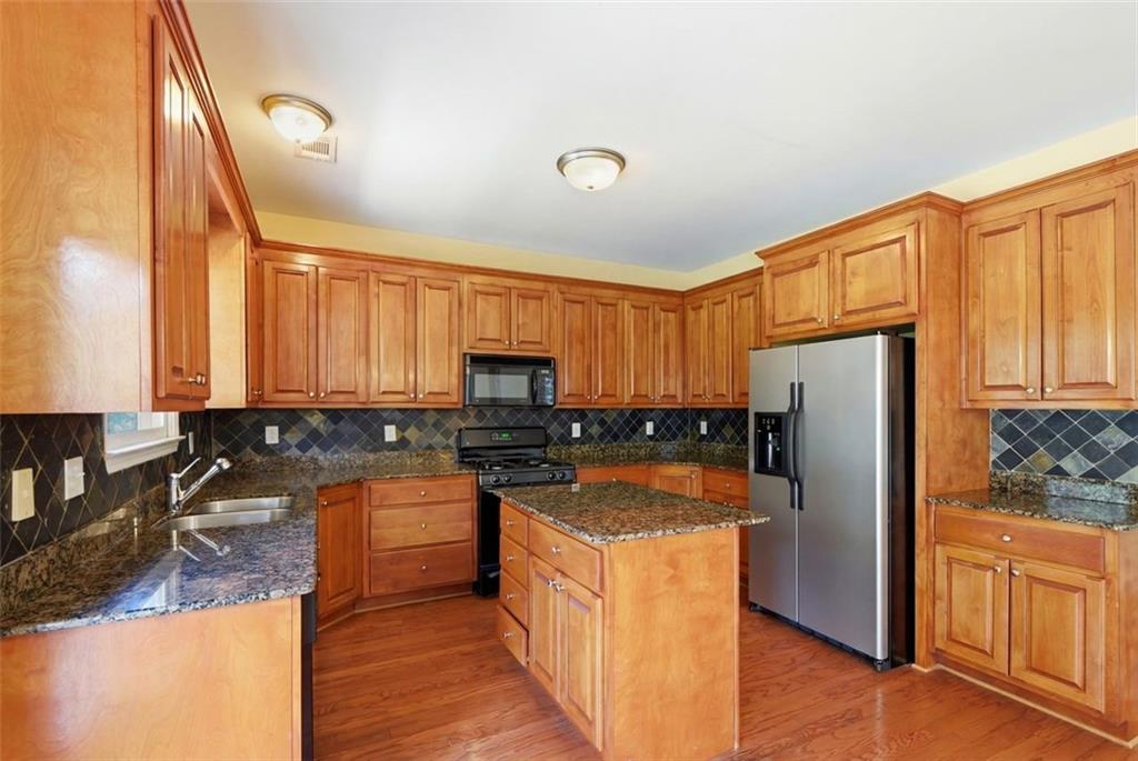 3420 Bulloch Lake Road Loganville, GA 30052 - Photo 23 of 57 a kitchen with stainless steel appliances granite countertop a refrigerator a stove and a sink with wooden floors