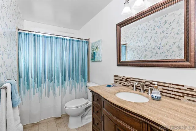 a bathroom with a granite countertop sink and a toilet