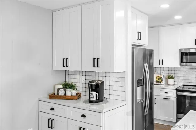 a kitchen with refrigerator a microwave a stove and white cabinets
