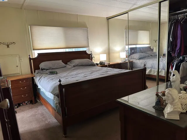 a bedroom with a bed and a mirror on the dresser