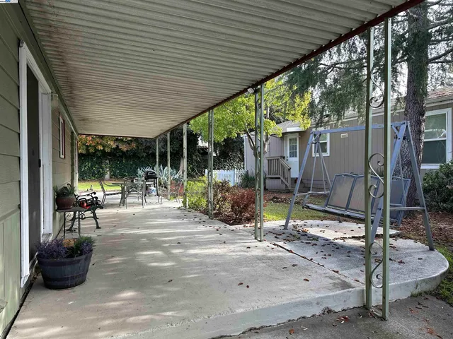 a view of a patio with table and chairs potted plants and floor to ceiling window