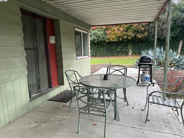 a view of a patio with a table and chairs under an roof deck