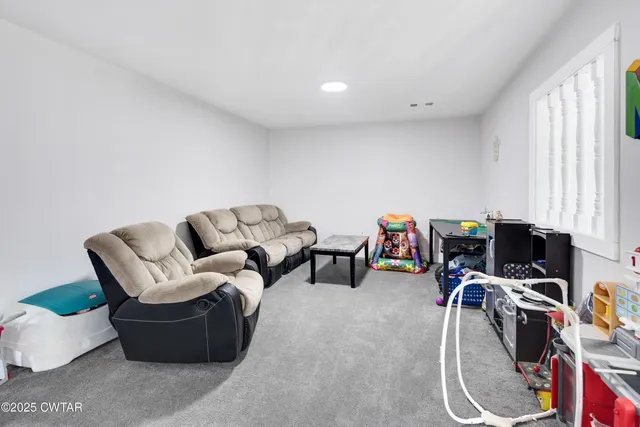 a living room with furniture a flat screen tv and a window